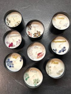 nine small cups with different designs on them sitting on a counter top next to each other