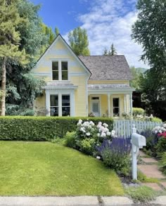 a yellow house surrounded by flowers and trees