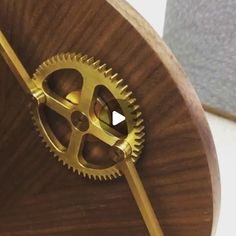 a wooden clock with gold gears on it's face and an arrow in the center