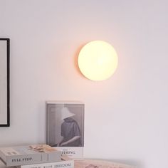 two books are sitting on a table next to a lamp and framed photograph in the corner