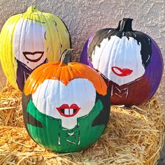 three painted pumpkins sitting on top of hay