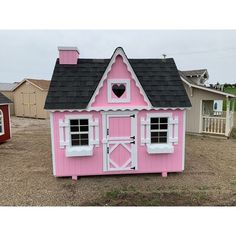 a pink and white doll house sitting on top of a dirt field