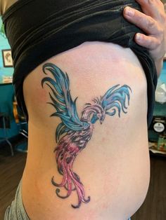 a woman with a tattoo on her stomach has a colorful bird design on her lower back