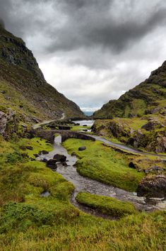 a winding road in the middle of a valley with grass and rocks on both sides