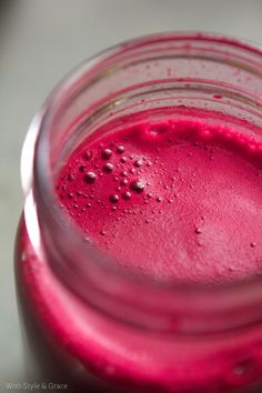 a glass filled with red liquid sitting on top of a table