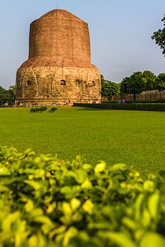 a large brick structure sitting in the middle of a lush green field next to trees