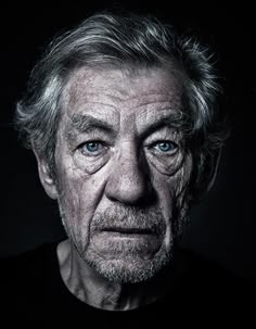 black and white photo of an old man with wrinkles on his face, looking at the camera