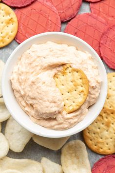 a bowl filled with crackers and dip surrounded by heart shaped cookies on a table