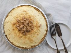 a pie sitting on top of a white plate next to a fork and spoons