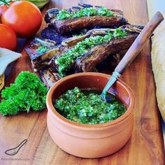 a wooden cutting board topped with meat and veggies next to a bowl of broccoli