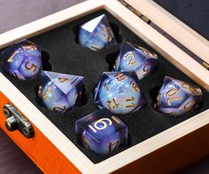 a wooden box filled with purple and gold dice