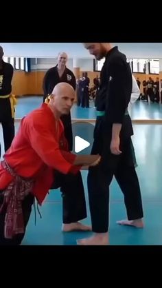 two men in red shirts and black pants doing karate