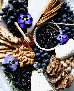 an assortment of cheeses, crackers and grapes on a plate