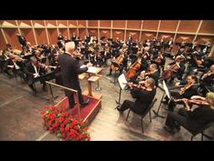 an orchestra conductor is standing in front of the orchestra