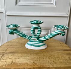 a green and white vase sitting on top of a wooden table