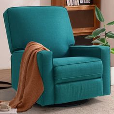 a teal chair with a blanket on it in front of a bookshelf