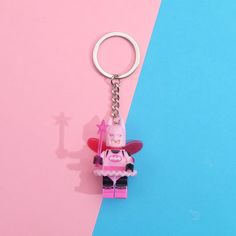 a pink and blue background with a lego keychain that has a pig on it