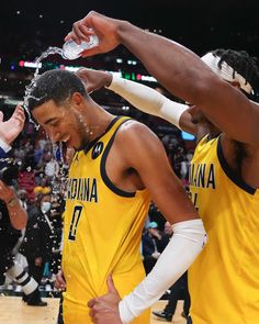 two men in yellow uniforms standing next to each other with water coming out of their mouths