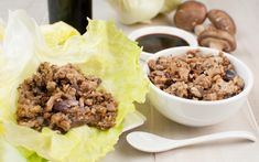 lettuce wraps filled with meat next to some dipping sauces and sliced mushrooms