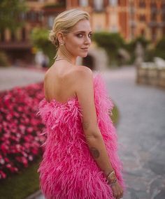 a woman in a pink feathered dress is posing for the camera