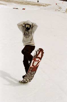 a man riding a snowboard on top of a snow covered slope with his hands behind his head