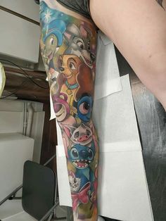 a woman's leg with tattoos on it and cartoon characters all over the arm