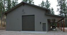 a garage with an open door on the side of it in front of some trees