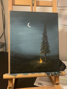 an easel with a painting on it and a lit tree