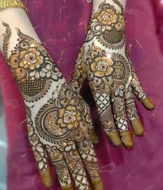 two hands with henna tattoos on them, one is showing off the intricate design