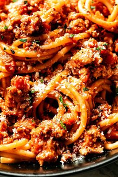 a plate full of spaghetti with meat sauce and parmesan cheese