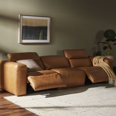 a living room with a brown leather couch and rugs on the wooden flooring