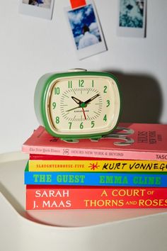 a stack of books sitting on top of a table next to a small alarm clock