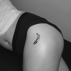 a black and white photo of a banana tattoo on the back of a woman's thigh