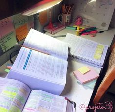 an open book sitting on top of a desk next to a pile of paper and pencils