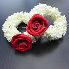 two red and white flowers are placed on a black surface with the word love spelled below them