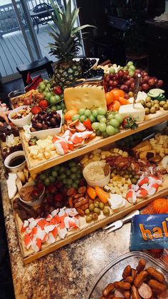 several trays of different types of food on a table with pineapples and grapes