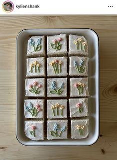 there are many small square cakes with flowers on them in a pan, and one is cut into squares