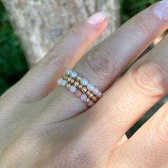 a woman's hand with three different rings on her fingers and one is wearing a gold band