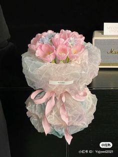 a bouquet of pink flowers sitting on top of a black table next to a radio