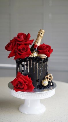 a cake decorated with roses and chocolates on a white table next to a bottle of champagne