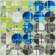 a quilt with blue and green circles on the front, along with an abstract design