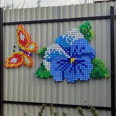 two colorful flowers made out of legos on a metal wall next to each other