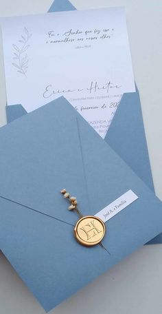 two blue envelopes with a gold monogrammed seal