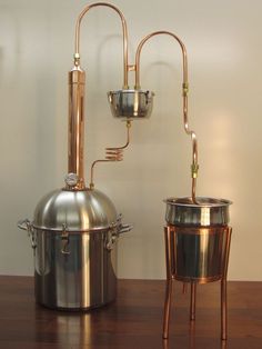 two pots and a kettle sitting on top of a wooden table next to each other