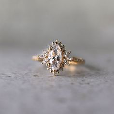 a close up of a diamond ring on a gray surface with white and gold accents