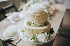 a three tiered cake sitting on top of a wooden table next to plates and silverware