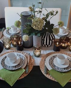 the table is set with black and white dishes, green napkins, and flowers