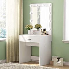 a white vanity in a green room with flowers on the counter and a mirror above it