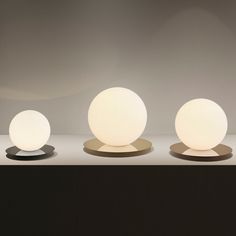 three white balls sitting on top of each other in front of a gray wall and floor