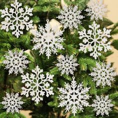 white snowflakes are hanging from the branches of a christmas tree